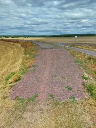 A small road ending in gravel and dirt road.の写真素材