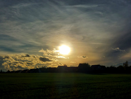 Row of houses on field in backlit evening scene.の写真素材