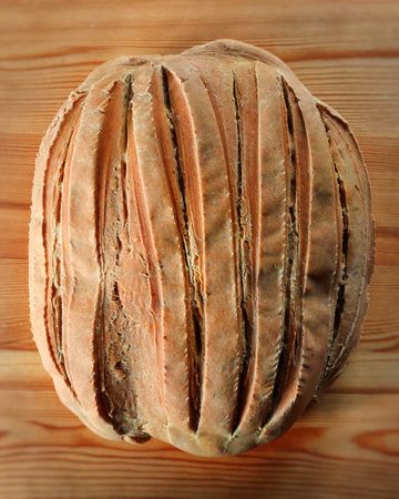 Loaf of home-baked bread on wooden board.