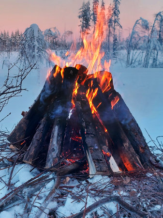 Bonfire in Swedish winter landscape at dusk.の写真素材