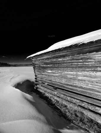 Conceptual shot of simple shed in northern Sweden in black and white with black sky.の写真素材