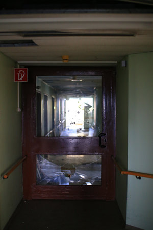 Cracked and damaged glass door in a hallway.の写真素材