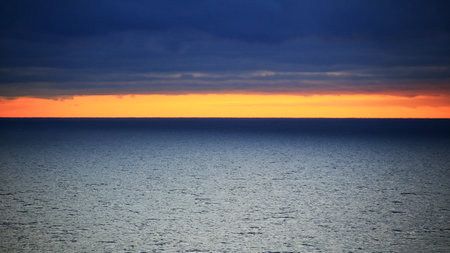 Orange horizon between dark clouds and Baltic sea.の写真素材