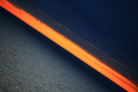 Creative diagonal shot of orange horizon between dark clouds and Baltic sea.の写真素材