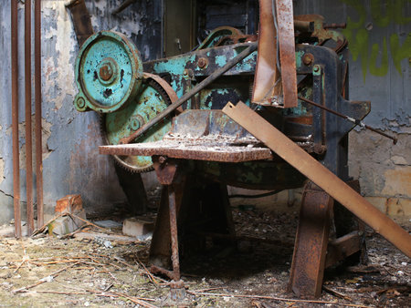 Rusted industrial machine in abandoned workshop surrounded by debris and peeling paint.の写真素材