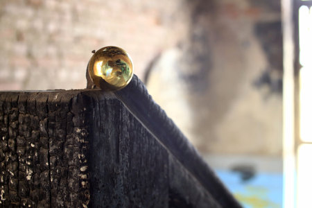 Burnt wood railing topped with brass sphere inside decayed interior space.の写真素材