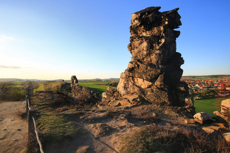Rock formation path beside sandstone cliff overlooking village and spring landscape in the Harz mountains, Germany.の写真素材