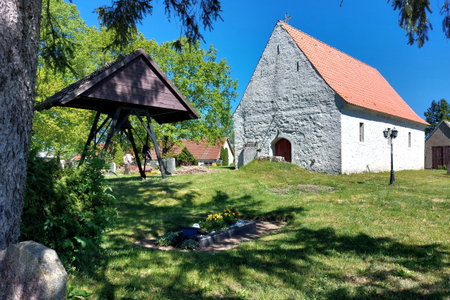 Church and bellframe on cemetery framed by trees and lawn in peaceful village Klein Bunzow.の写真素材