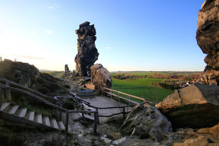 Sandstone spire overlook with railing and stairs above fields and houses in the Harz region, Germany.の写真素材
