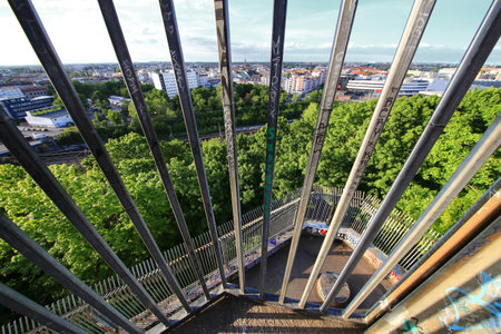Steel bars overlooking dense treetops and Berlin cityscape from a high urban observation point on Flak tower III.の写真素材