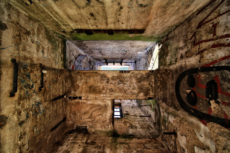 Abandoned concrete interior with graffiti and ceiling opening showing blue sky and light.の写真素材
