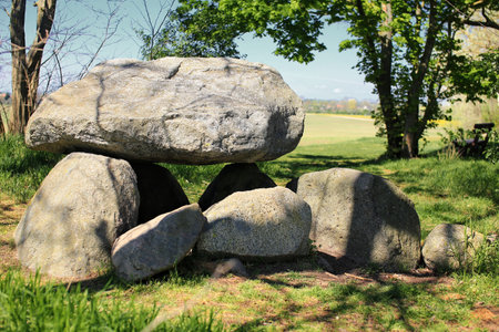 Large dolmen Hoher Stein in Germany under leafy trees in a clearing near open fields and rural countryside.の写真素材