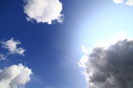 Bright sunlit sky with cumulus clouds and blue gradient captured on a clear spring day.の写真素材
