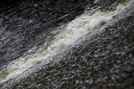 Diagonal rushing water showing foamy turbulence across a sloped stream surface.の写真素材