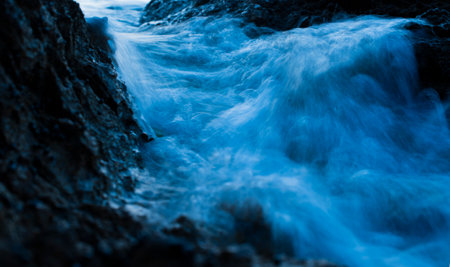 Close up of blue water flowing over rocks in the sea. Long exposure.の写真素材