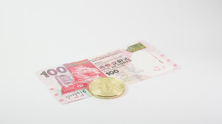 Background with Bitcoin cryptocurrency coins and Hong Kong dollar. Bitcoin cryptocurrency concept, Bitcoin BTC virtual money and Hong Kong dollar banknotes.の写真素材