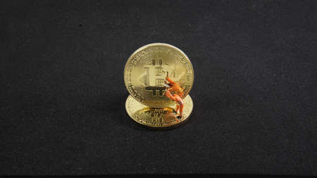 Bitcoin mining miniature worker on black background. small figure holding mattock digging on More...