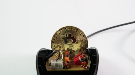 Bitcoin mining miniature worker on white background. small figure holding mouse digging on More...