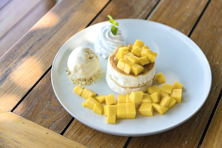 Mango and vanilla ice cream with fluffy cake in white plate on the wooden table. Selective focus.の写真素材