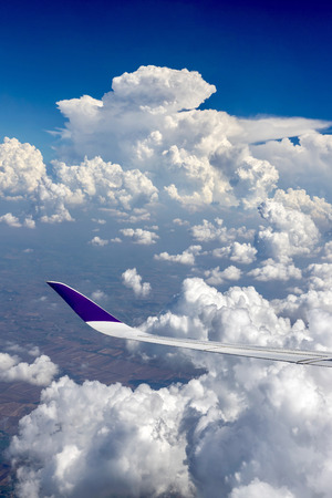 View from airplane window on the wing  over the white cloud and blue sky in the sunny day.の写真素材