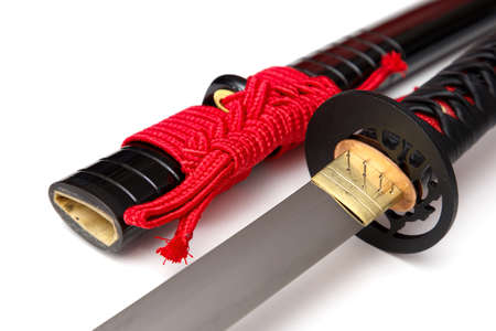 Japanese sword with red cord   steel fitting and shiny black scabbard on white background. Selective focus.の写真素材