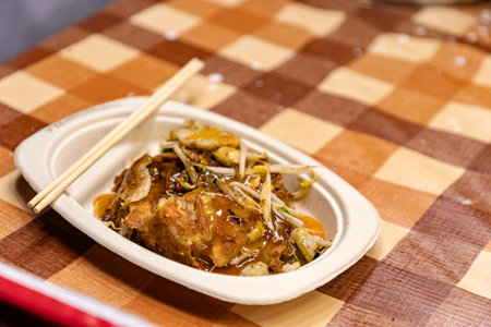 Hoy-Tod Delicious Thai food made from oysters, flour, egg and fried until crispy. Famous Thai food. Put in a disposable paper plate on a table covered with plastic checkered cloth. Selective focus.の写真素材