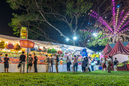 Bangkok, Thailand - Dec 8, 2022: Visitors to the Red Cross Fair at Lumpini Park, held from December 8-18, 2022, are shooting airsoft rifles to win colorful dolls. à¸ºBeautiful lights. Motion blur.のeditorial素材