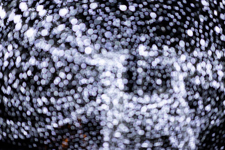 An image of lots of blue-and-white bokeh on a black background, captured by blurred LED lights at night.の写真素材