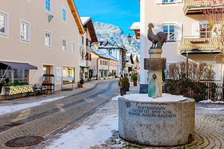 Garmisch-Partenkirchen, Bavaria, Germany â November 28, 2025: The Rottbrunnen fountain with a rooster statue in the picturesque old town of Partenkirchen, surrounded by pastel houses, cobblestone streets, and a mountain backdrop.のeditorial素材