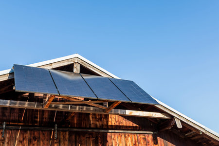 Solar panels mounted on the roof of a wooden house generating clean renewable energy under clear...