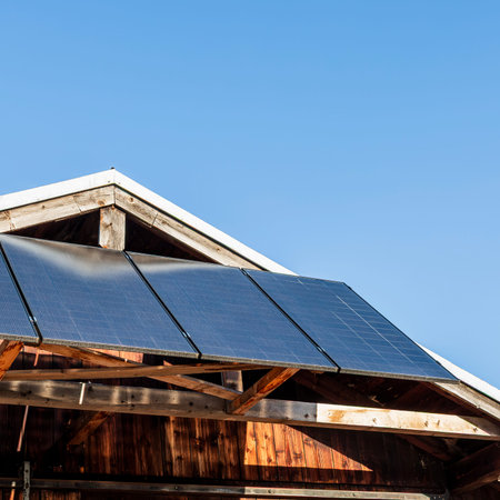 Solar panels mounted on the roof of a wooden house generating clean renewable energy under clear...