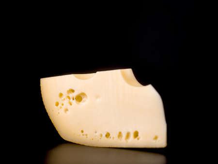 piece of cheese maasdam on black bacground