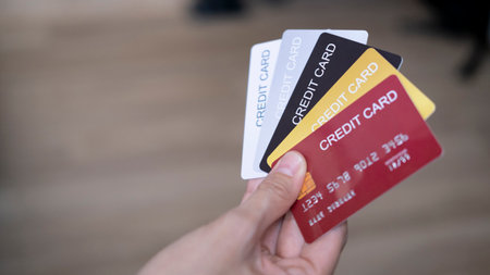 Hand is hold five credit cards. Black gold silver and red color credit cards. isolated on wooden...