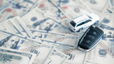 Car key and toy car on money suggesting car loan financing, monthly payment burden and economic...