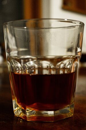 a glass of whiskey on a wood table