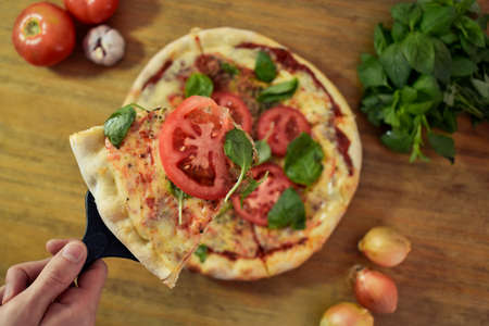 serving pizza with tomato, basil, mozzarella at homeの写真素材