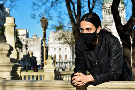 european young man looking on the balcony with a mask