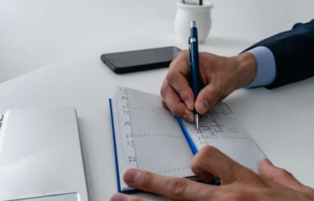 businessman highlighting in a corporate notebook with a mechanical pencil May 1, Labor Day, wearing...