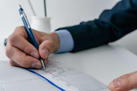 young businessman writing with a mechanical pencil in his notebook may 1 labor day. wearing blue...