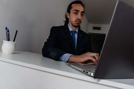 businessman doing work at home in monochromatic blue suit, work day, vertigo feelingの写真素材