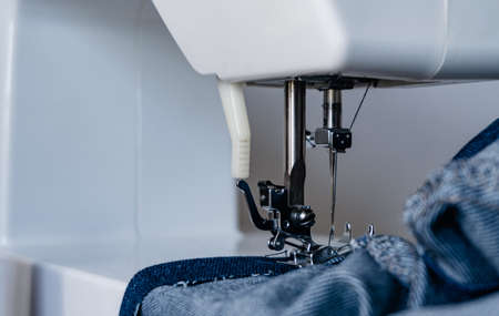 sewing machine being used. A close-up shows a needle going through denim jean fabric. quarantine...