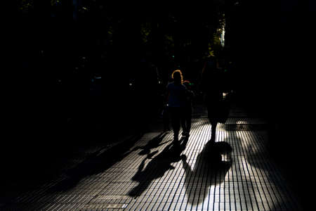 shadows of a family on the street walking hand in hand with mother. father daughter and son. adoption of children. photo against hopeful light.の写真素材