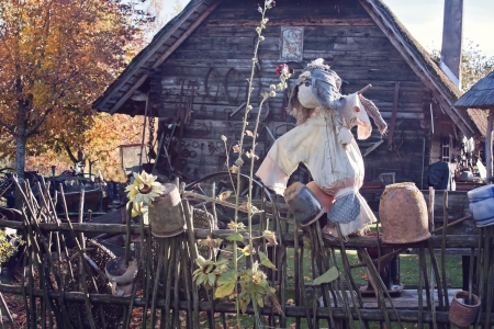 scarecrow on a fence, old wooden house in a backgroundの写真素材