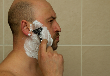Man shaving his face with the razor blade through shave foam. Men skin care concept.の写真素材