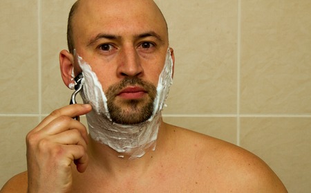 Serious guy shaving his beard