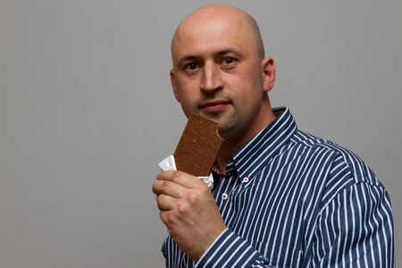 young man holding a chocolate barの写真素材