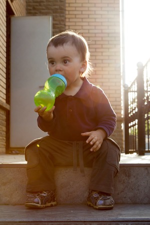 childhood and people concept - little baby drinking from spout cup.の写真素材