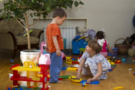 three children playing on floor with colored toys.の写真素材