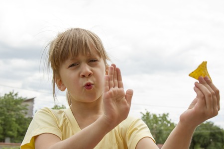 cute little girl offering potato chips with unhappy expressionの写真素材