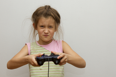 Girl with joystick. Excited little girl playing video game and smilingの写真素材